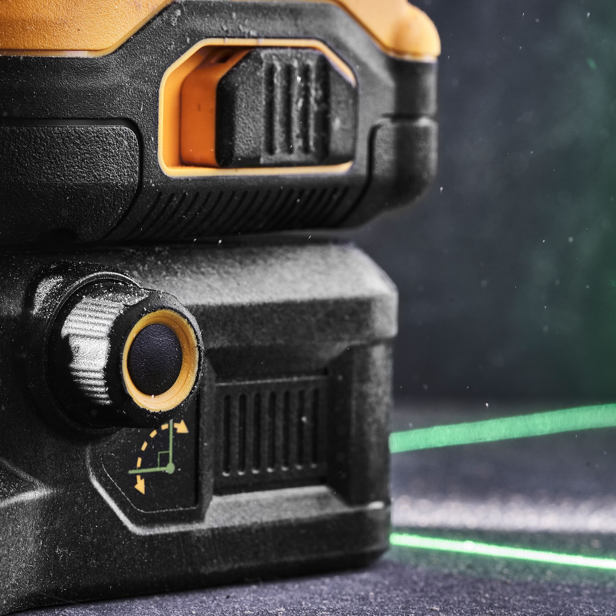 Close-up of a DEWALT laser level tool showing its adjustment knob and casing, with visible green laser lines projecting in the background.