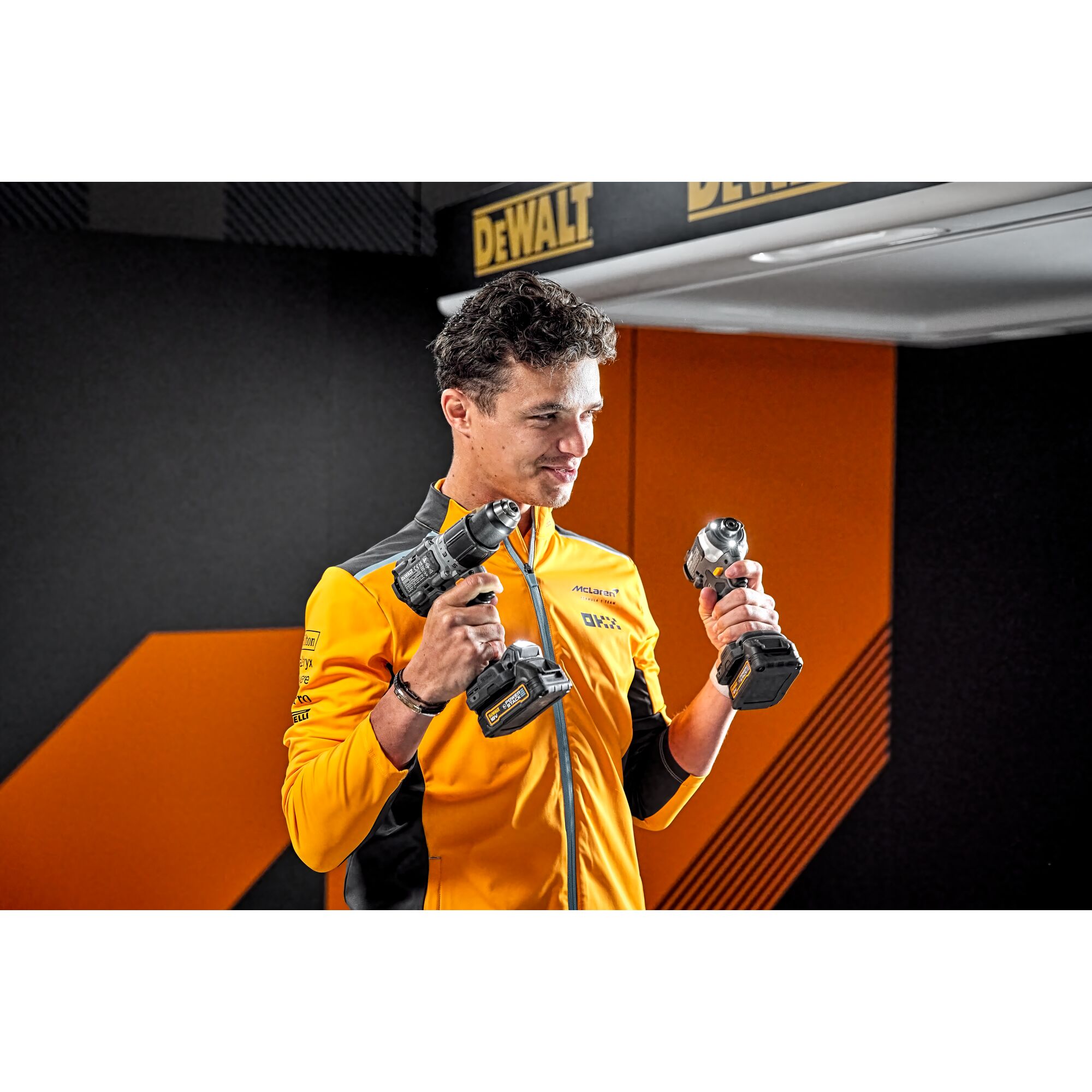 McLaren driver Lando Norris holding two Limited Editon DEWALT/McLaren Drill Drivers