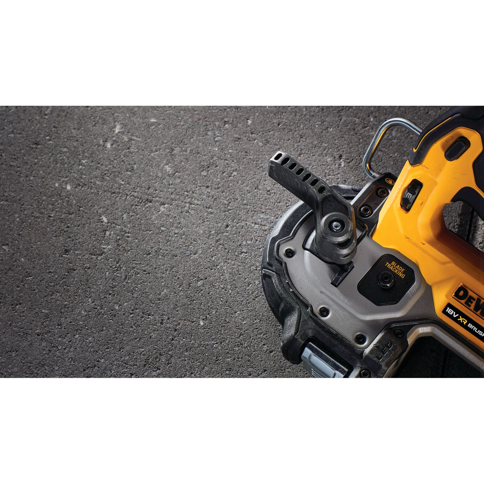 Close-up of a DEWALT power tool, yellow and black, on a textured surface, showing part of handle and base.