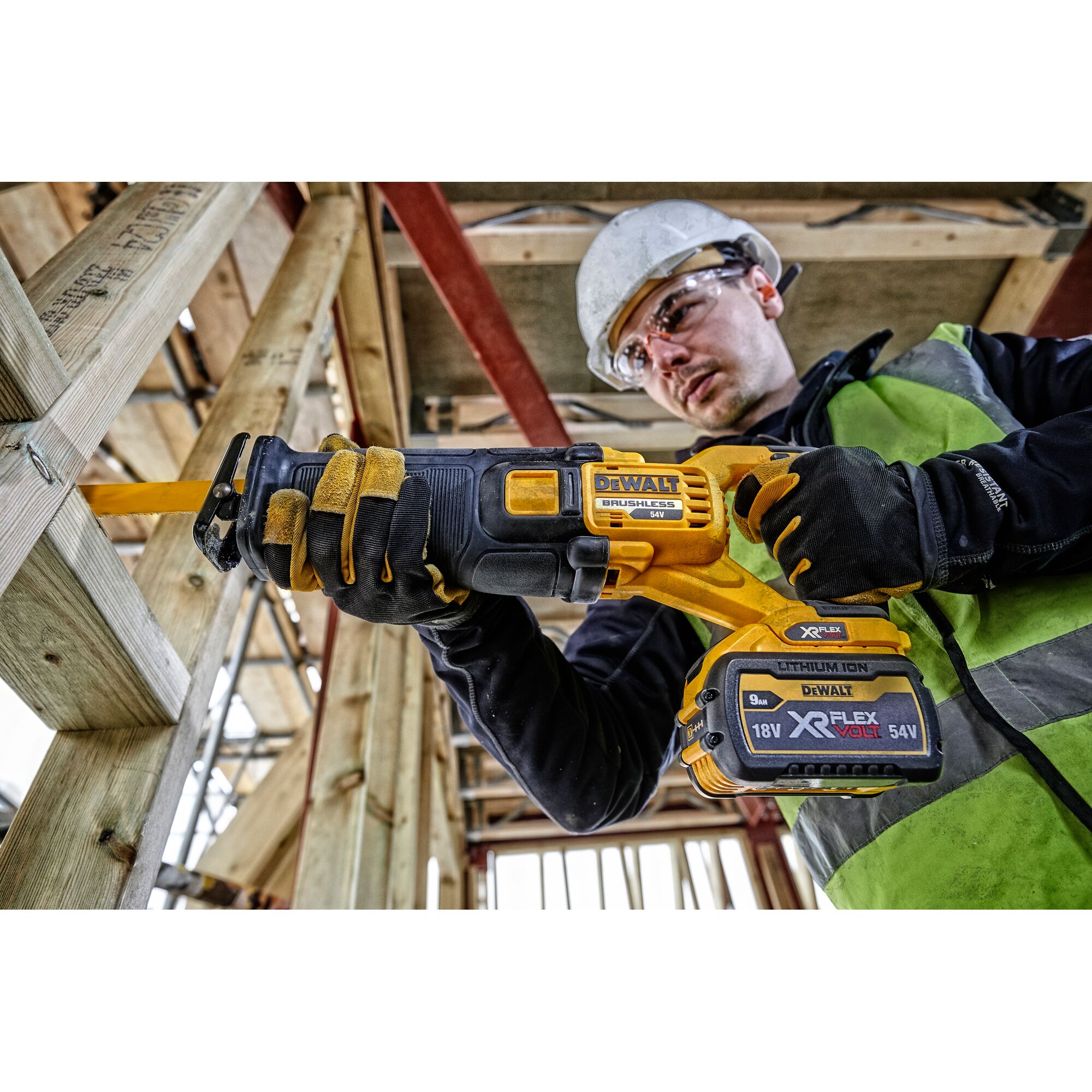 Worker using a DEWALT DCS389N cordless reciprocating saw on wood at a construction site.
