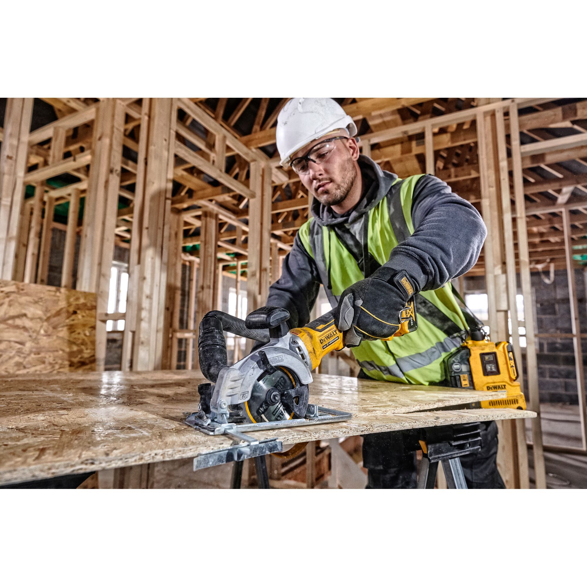 Worker uses DEWALT circular saw to cut wood in a building under construction.