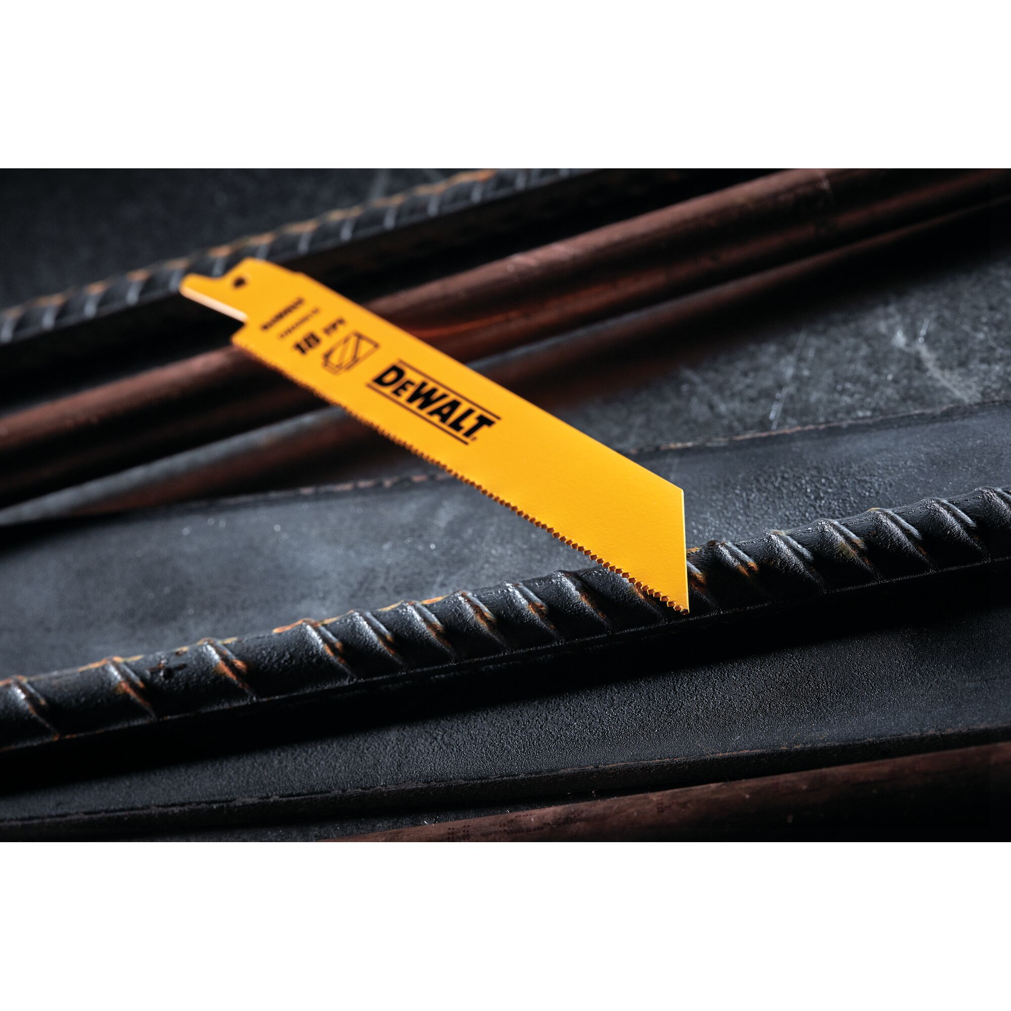 A close-up of a DEWALT DW4811 yellow reciprocating saw blade positioned across metal rebar on a dark surface.